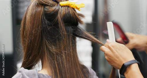 Woman having hair straightening treatment in hair salon photo