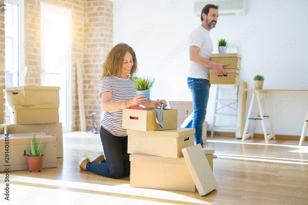 Middle age senior couple moving to a new house, smiling woman holding cardboard boxes and packaging Middle age senior couple moving to a new house, smiling woman holding cardboard boxes and packaging