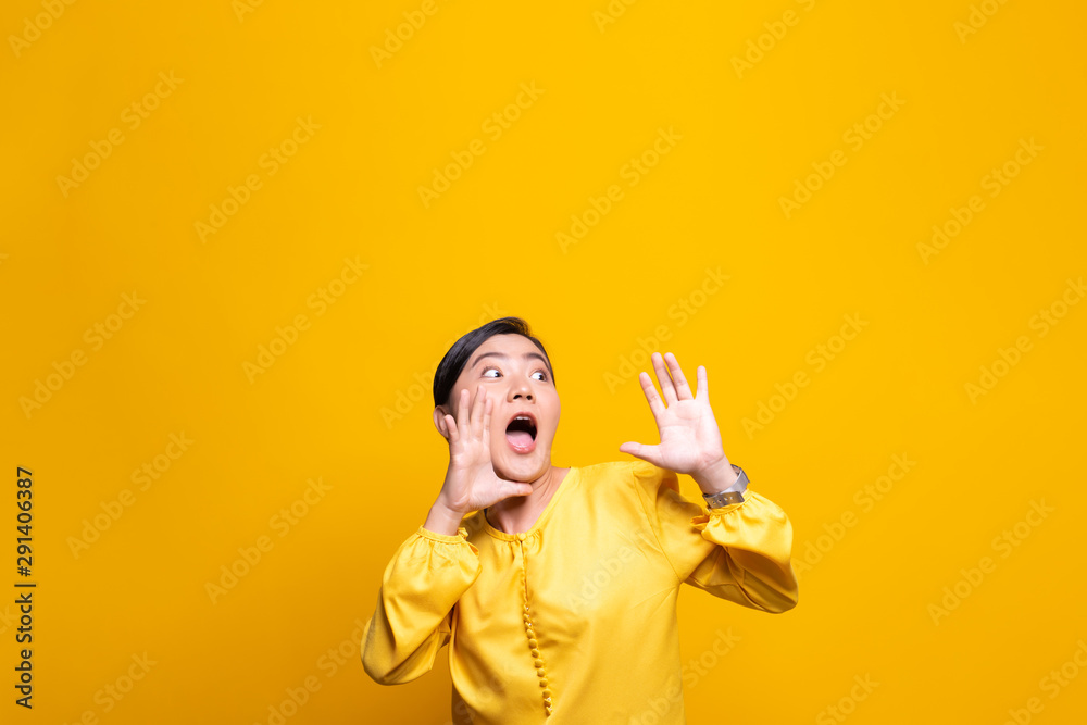 Happy woman making shout gesture isolated over yellow background Happy woman making shout gesture isolated over yellow background