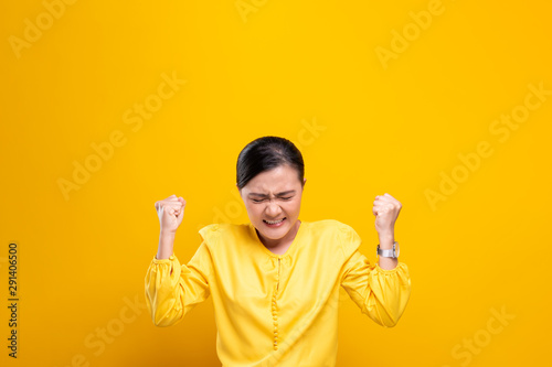 Angry woman standing isolated over yellow background