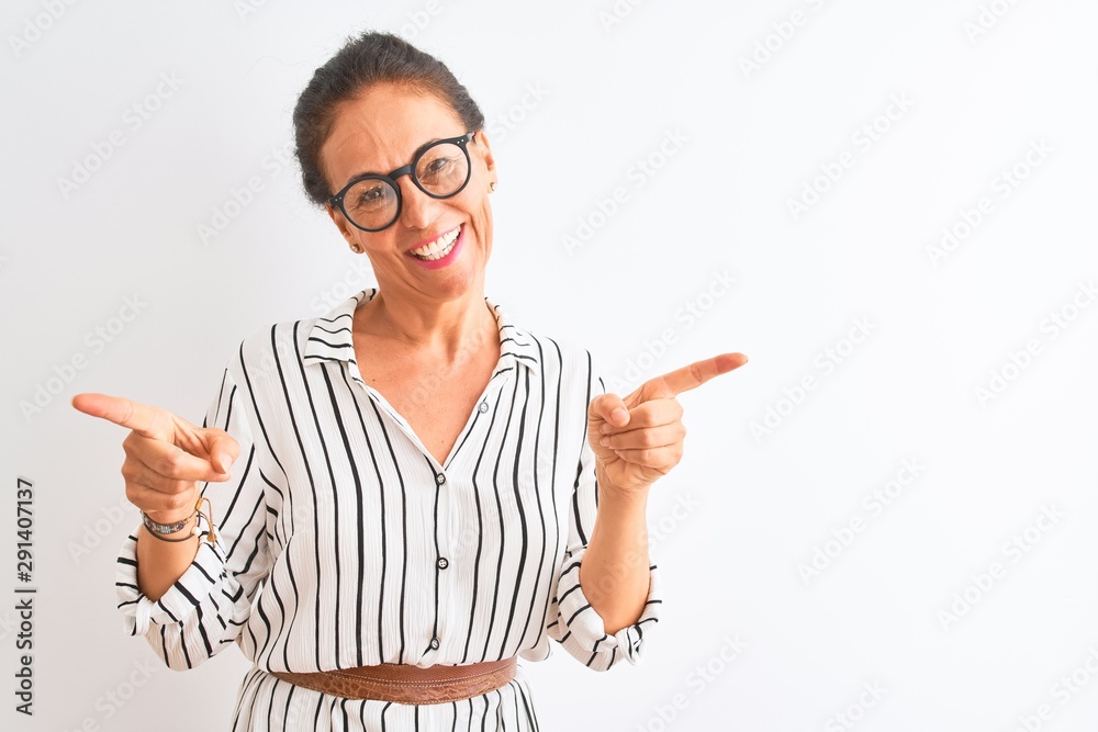 Middle age businesswoman wearing striped dress and glasses over isolated white background smiling confident pointing with fingers to different directions. Copy space for advertisement Middle age businesswoman wearing striped dress and glasses over isolated white background smiling confident pointing with fingers to different directions. Copy space for advertisement