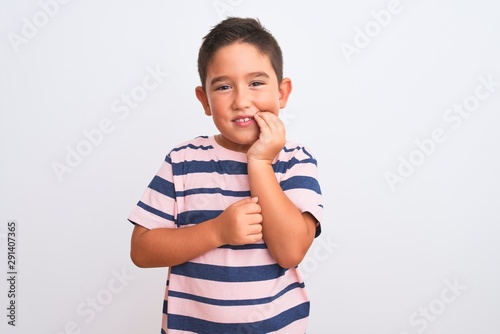 Beautiful kid boy wearing casual striped t-shirt standing over isolated white background touching mouth with hand with painful expression because of toothache or dental illness on teeth