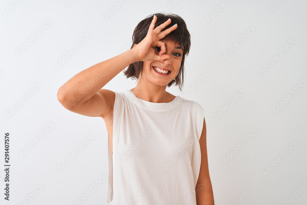 Young beautiful woman wearing casual t-shirt standing over isolated white background doing ok gesture with hand smiling, eye looking through fingers with happy face. Young beautiful woman wearing casual t-shirt standing over isolated white background doing ok gesture with hand smiling, eye looking through fingers with happy face.