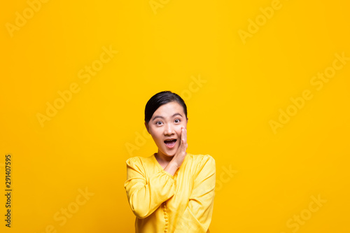 Woman make gossip gesture isolated over yellow background © chajamp