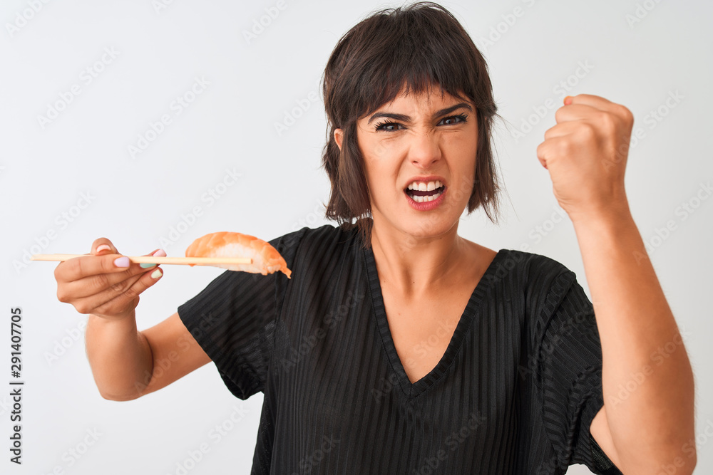 Beautiful woman eating salmon nigiri sushi using chopsticks over isolated white background annoyed and frustrated shouting with anger, crazy and yelling with raised hand, anger concept