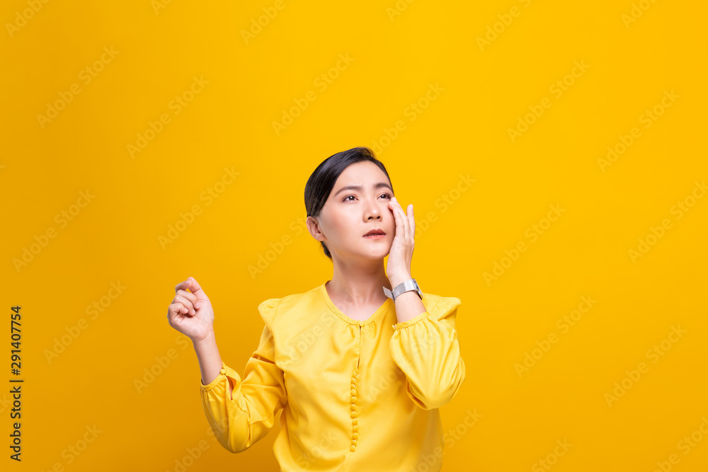 Woman has eyes pain isolated over yellow background