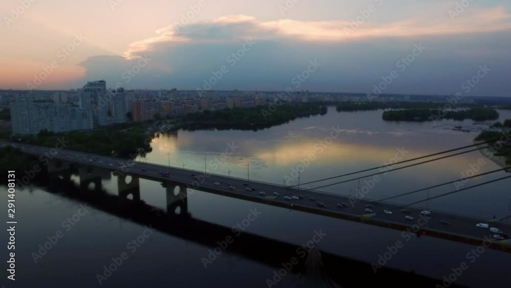 Drone view car traffic on suspension bridge over river on evening city landscape Drone view car traffic on suspension bridge over river on evening city landscape