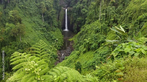 Panning shot of Sopoaga Waterfall in Samoa amongst the lush forest canopy photo