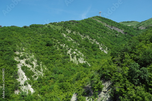 Mountain peaks covered with greenery and blue sky.