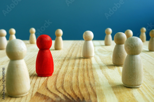 Inclusion social concept. Red figurine between wooden figurines.