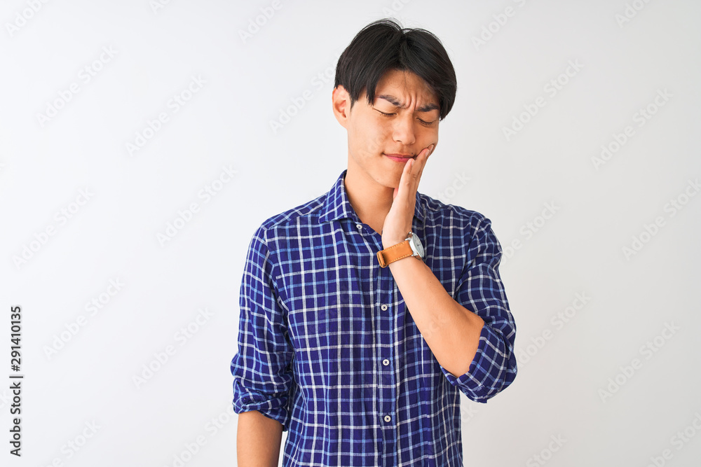 Young chinese man wearing casual blue shirt standing over isolated white background touching mouth with hand with painful expression because of toothache or dental illness on teeth. Dentist concept. Young chinese man wearing casual blue shirt standing over isolated white background touching mouth with hand with painful expression because of toothache or dental illness on teeth. Dentist concept.