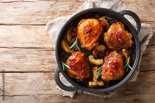 Quadro su tela Crispy fragrant baked chicken thighs with apples, cranberries and rosemary closeup in a pan on the table