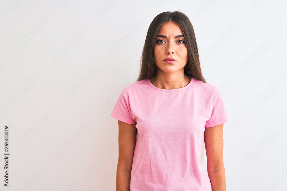 Fototapeta premium Young beautiful woman wearing pink casual t-shirt standing over isolated white background Relaxed with serious expression on face. Simple and natural looking at the camera.