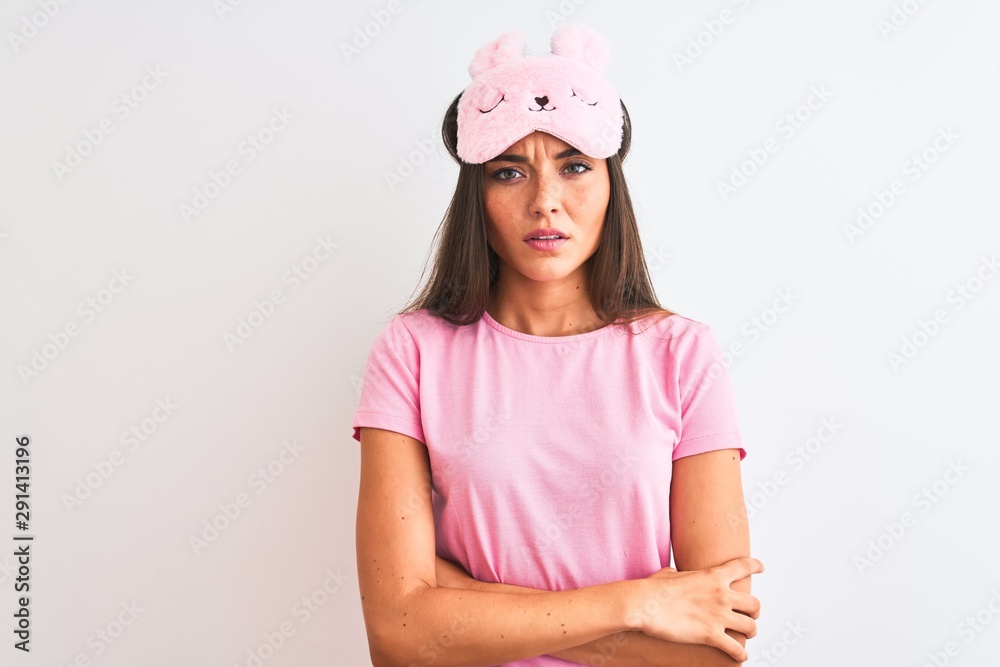 Young beautiful woman wearing sleep mask standing over isolated white background skeptic and nervous, disapproving expression on face with crossed arms. Negative person. Young beautiful woman wearing sleep mask standing over isolated white background skeptic and nervous, disapproving expression on face with crossed arms. Negative person.