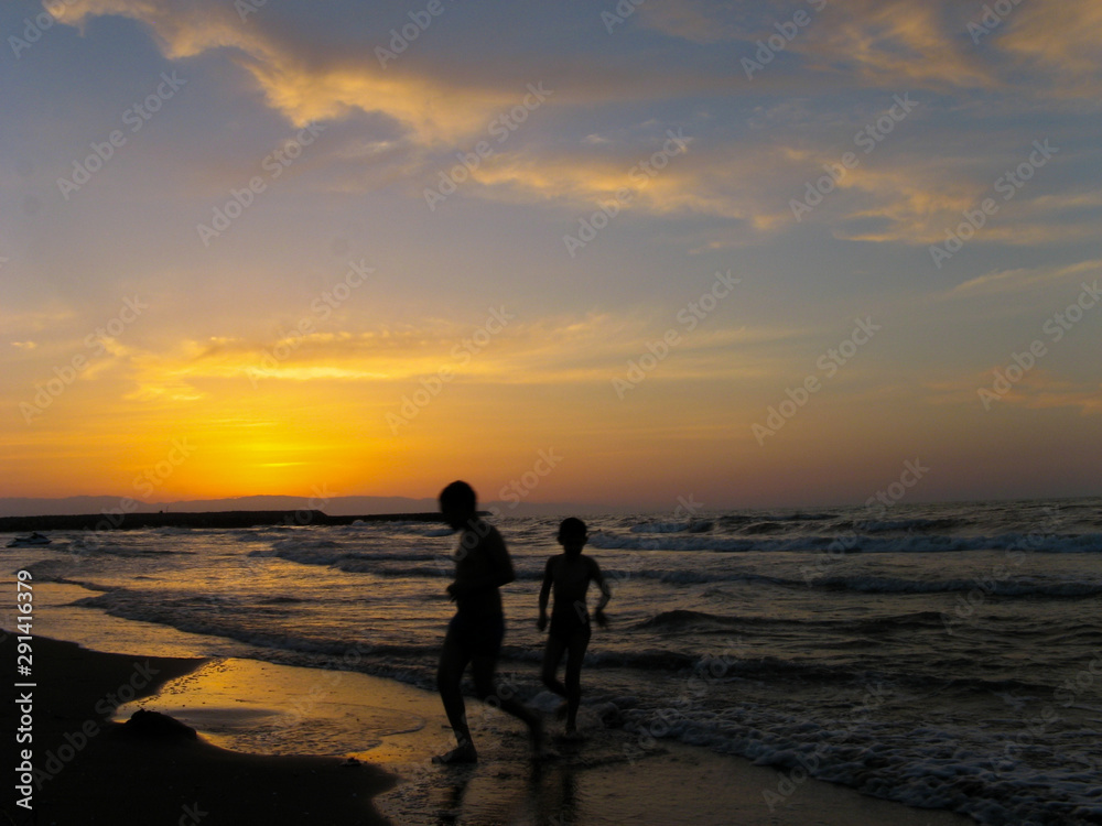Children play at beach sunset. children playing sea beach sunset. Two boys running on the beach at the sunset time with space for text. Children play at beach sunset. children playing sea beach sunset. Two boys running on the beach at the sunset time with space for text.