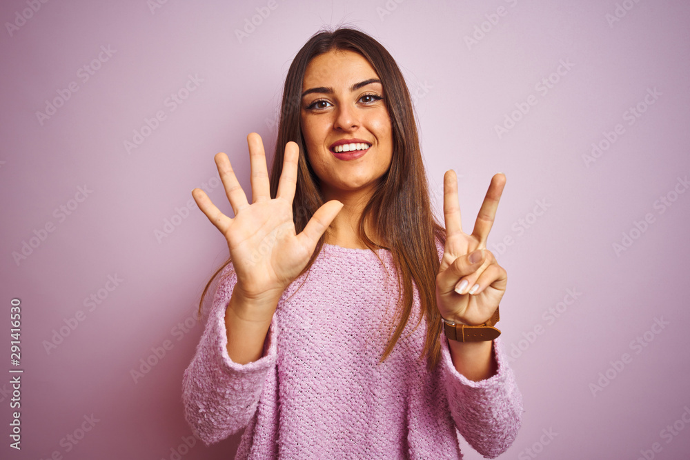 Young beautiful woman wearing casual sweater standing over isolated pink background showing and pointing up with fingers number seven while smiling confident and happy.