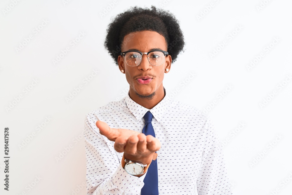 Young african american businessman wearing tie and glasses over isolated white background looking at the camera blowing a kiss with hand on air being lovely and sexy. Love expression. Young african american businessman wearing tie and glasses over isolated white background looking at the camera blowing a kiss with hand on air being lovely and sexy. Love expression.