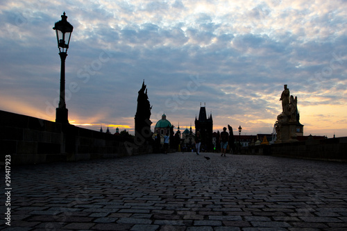 Silhouettes Charles Bridge, Old Town Tower, statues and happy tourists at sunrise, Prague, Czech Republic