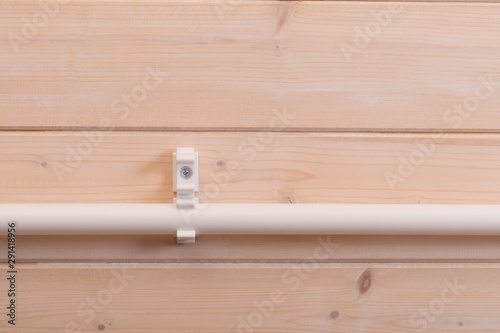 on a light wooden wall, polypropylene pipe, fixed in one of two mounts