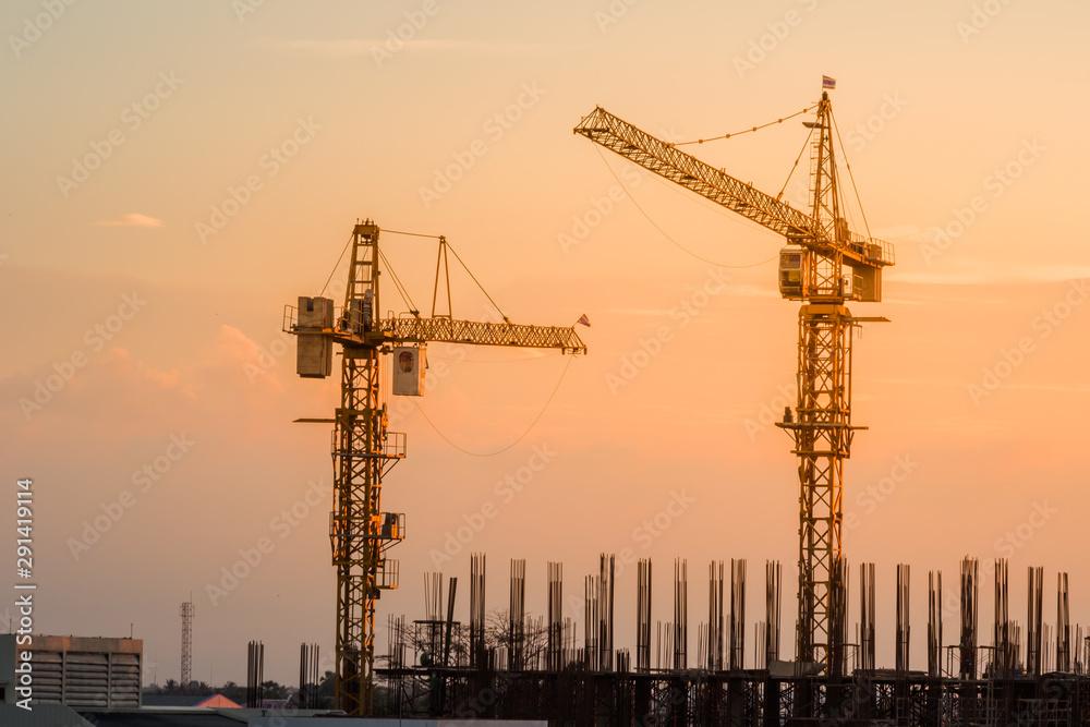 construction canes over building site on sunset sky in the evening construction canes over building site on sunset sky in the evening