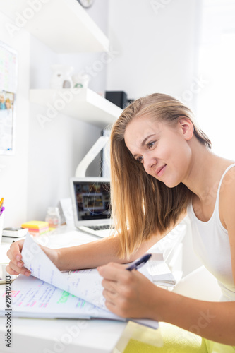 Teenage girl studing for school, doing homework on a sunny Sunday morning in a lovely, bright room