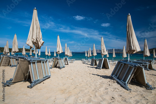 Scenic Sardinia island landscape. Italy sea ​​coast with azure clear water. Beach with umbrellas and loungers ready for the high season to start