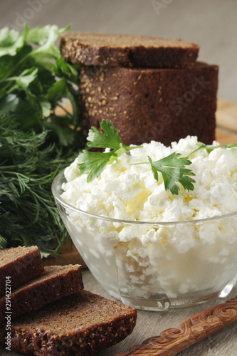 A bowl with cottage cheese, a bunch of green and rye bread