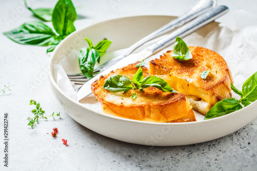 Fried sandwiches with cheese and basil on white plate.