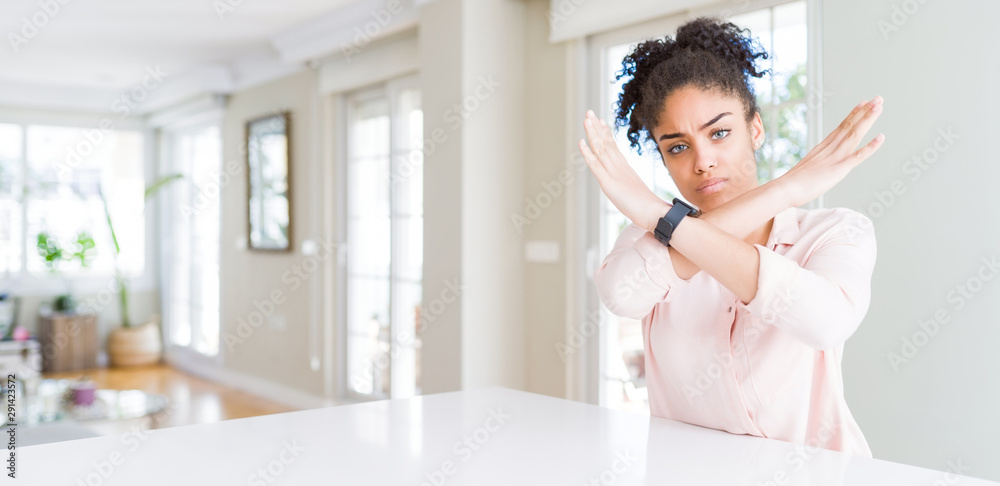 Wide angle of beautiful african american woman with afro hair Rejection expression crossing arms doing negative sign, angry face