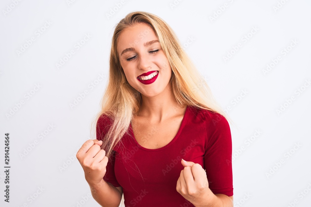 Young beautiful woman wearing red t-shirt standing over isolated white background very happy and excited doing winner gesture with arms raised, smiling and screaming for success. Celebration concept.