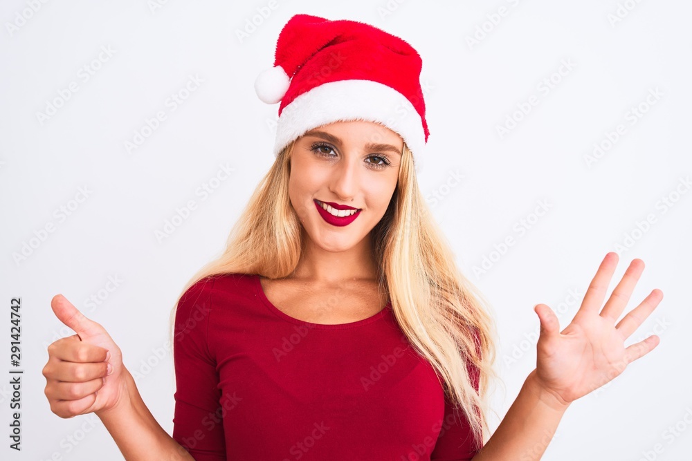 Young beautiful woman wearing Christmas Santa hat over isolated white background showing and pointing up with fingers number six while smiling confident and happy. Young beautiful woman wearing Christmas Santa hat over isolated white background showing and pointing up with fingers number six while smiling confident and happy.