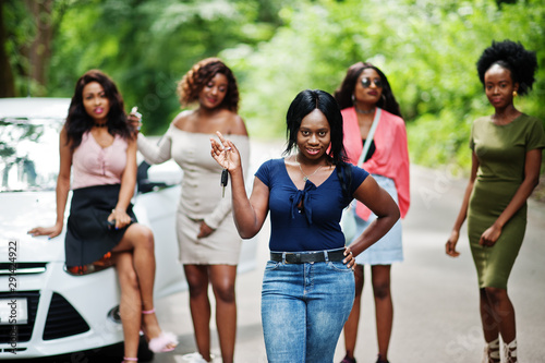 Group of five happy african american girls posed against car, one of them show keys. © AS Photo Family