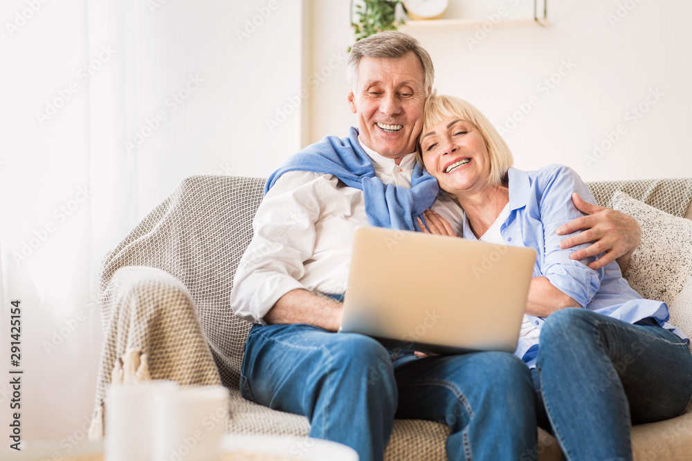 Loving mature couple watching film on laptop computer Loving mature couple watching film on laptop computer