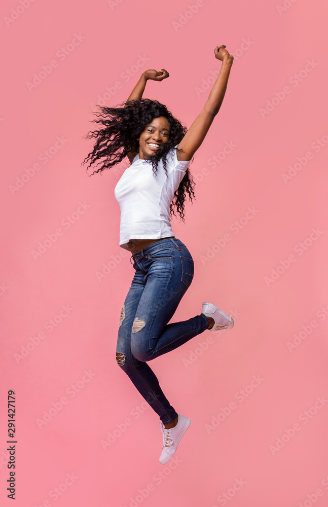 Smiling young african woman jumping in air