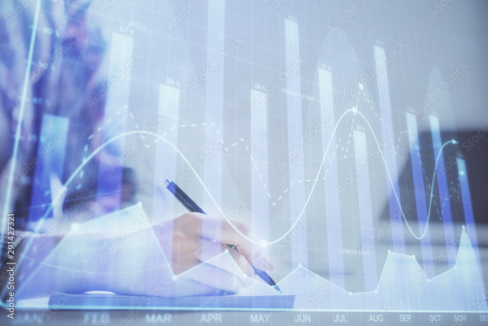 A woman hands writing information about stock market in notepad. Forex chart holograms in front. Concept of research. Double exposure A woman hands writing information about stock market in notepad. Forex chart holograms in front. Concept of research. Double exposure