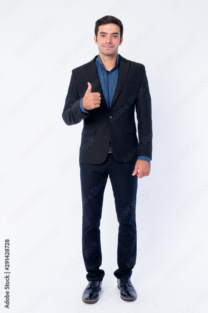 Full body shot of happy young handsome Persian businessman giving thumbs up Full body shot of happy young handsome Persian businessman giving thumbs up