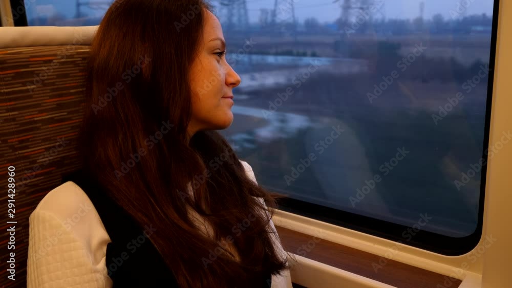 Optimistic passenger lady travel by high speed train, evening time. Woman relaxed sitting near window, look to rural outdoors. Modern bullet car travelling from Shanghai to Beijing