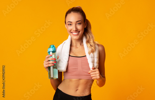 Fitness Girl Holding Water Bottle Posing On Yellow Background © Prostock-studio