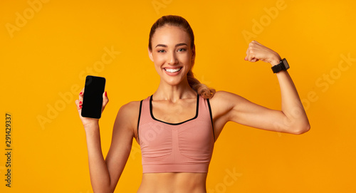 Girl Holding Smartphone Showing Muscles On Yellow Background, Mockup, Panorama
