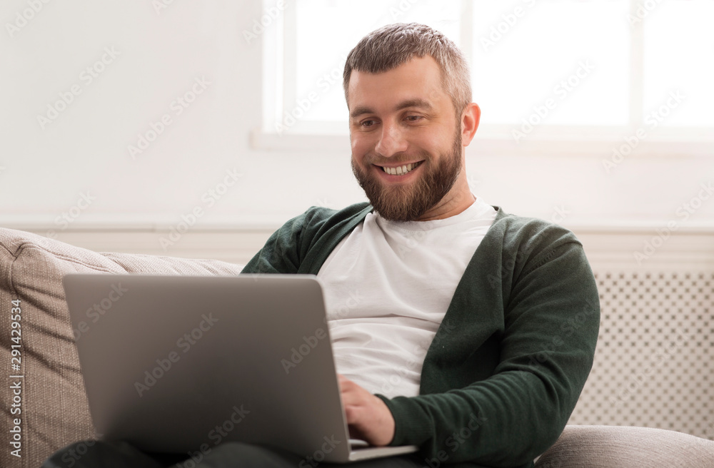 Smiling man working on laptop online at home Smiling man working on laptop online at home