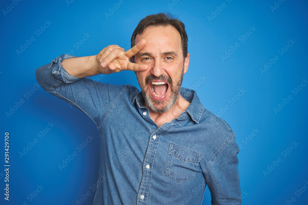 Handsome middle age senior man with grey hair over isolated blue background Doing peace symbol with fingers over face, smiling cheerful showing victory Handsome middle age senior man with grey hair over isolated blue background Doing peace symbol with fingers over face, smiling cheerful showing victory