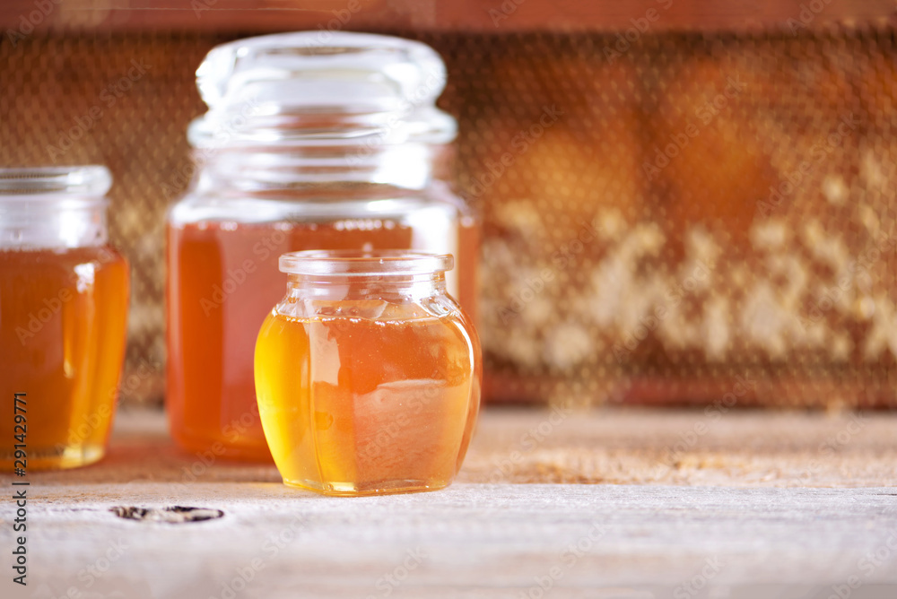 Honey products background. Honeycomb frame, bee pollen granules, honey in glass pot on grey concrete background. Copy space. Autumn harvest concept. Honey products background. Honeycomb frame, bee pollen granules, honey in glass pot on grey concrete background. Copy space. Autumn harvest concept.