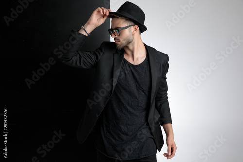 attractive young man holding hat on black and white background