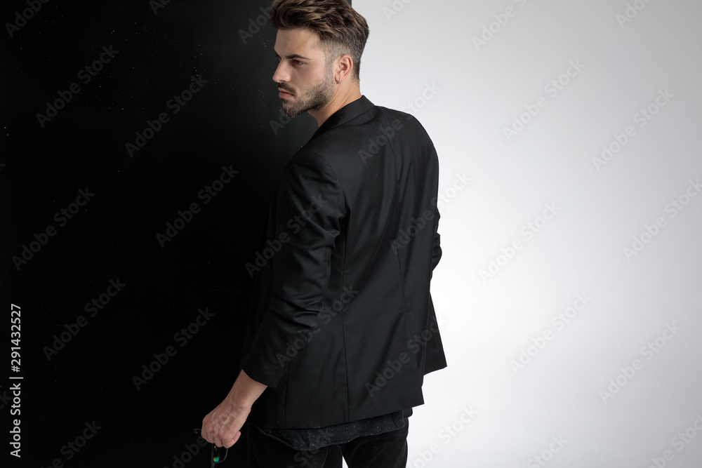 back view of smart casual man holding sunglasses in studio - obrazy, fototapety, plakaty 