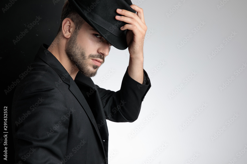 confident young man holding black hat in studio confident young man holding black hat in studio