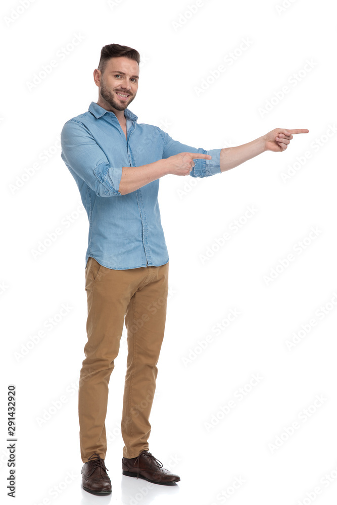 casual man standing and pointing sideways happy