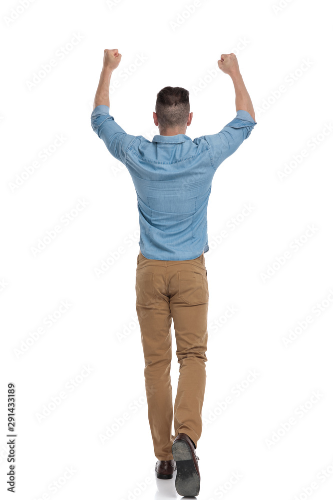 casual man walking with hands up in the air victorious casual man walking with hands up in the air victorious