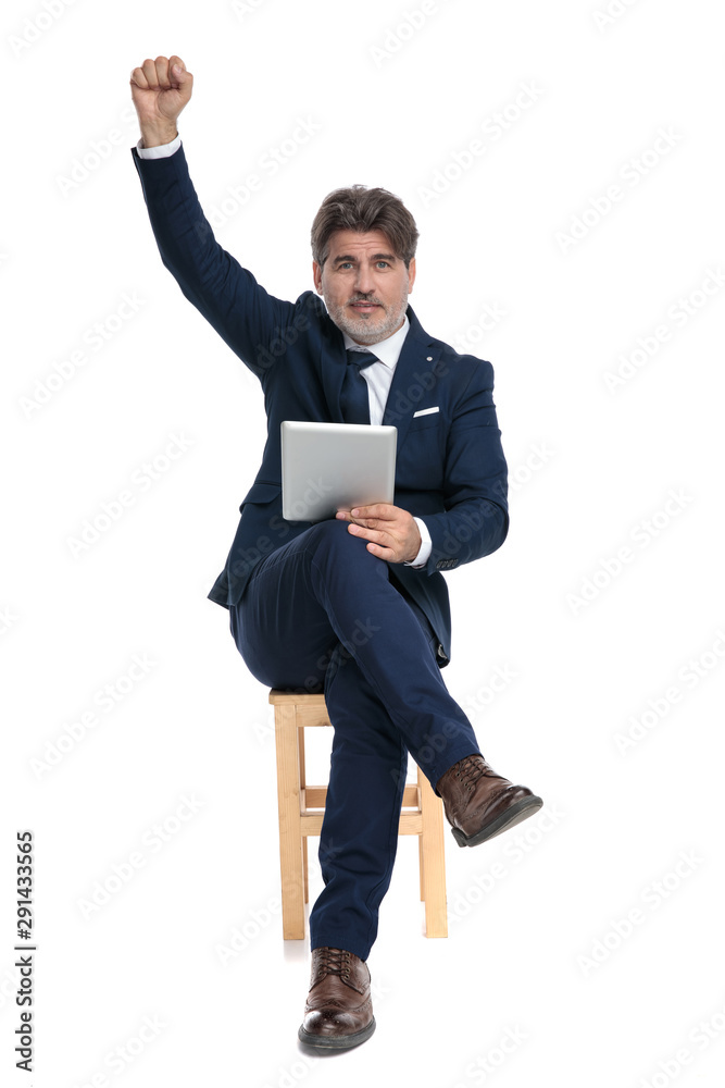 businessman sitting with fist up holding his tablet victorious businessman sitting with fist up holding his tablet victorious