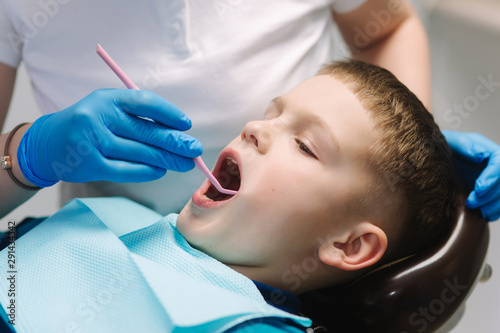 Close up of young boy sitting on the dental chair at the office. Children s dentist examination baby teeth