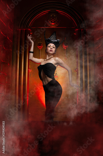 Evil stylish woman witch with big black hat on dark scary smoky background alone